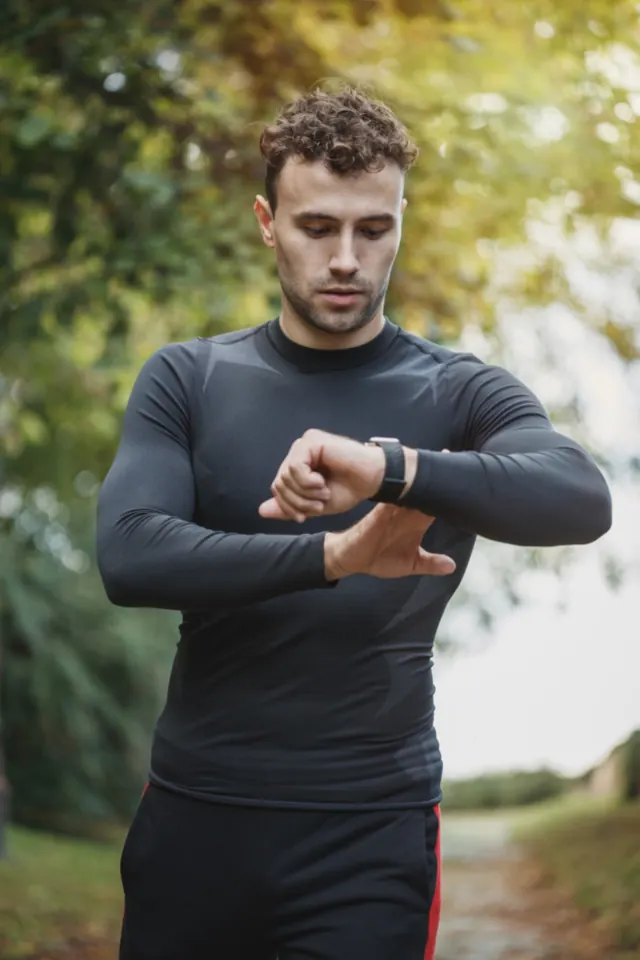 Man in a long-sleeve training top checking his watch