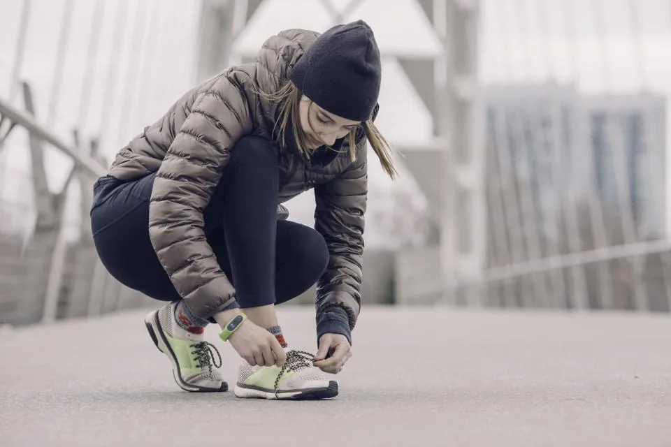 Woman in a padded jacket tying her running shoes