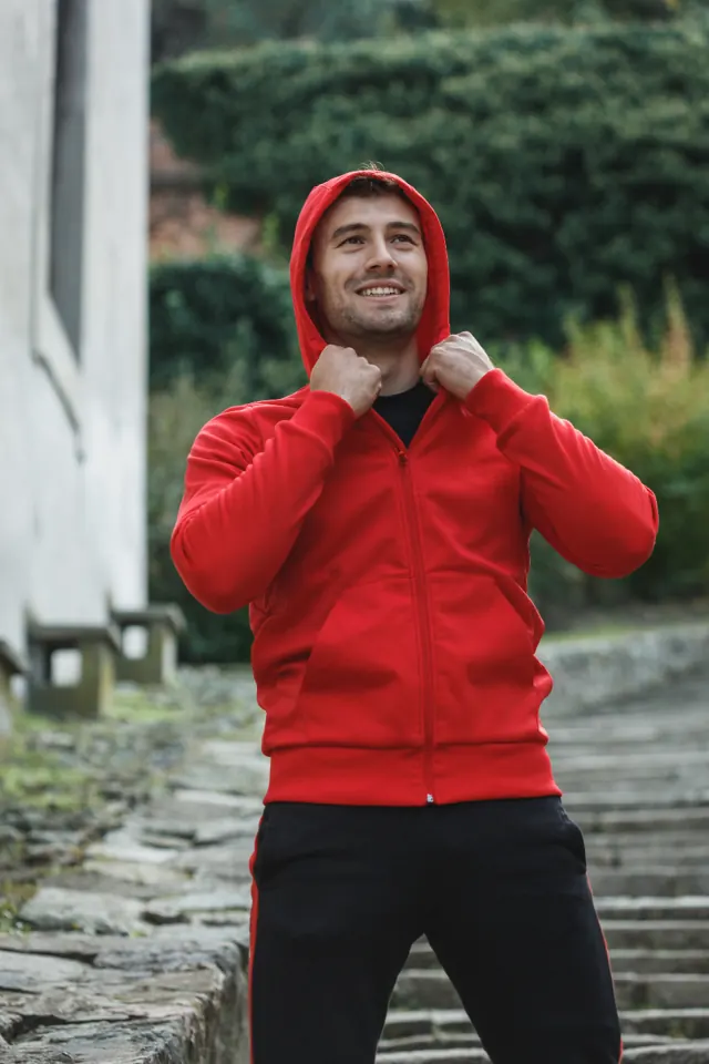Man wearing a red hooded track jacket outdoors