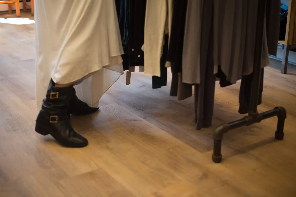 Clothing rail in a store with a customer trying on boots